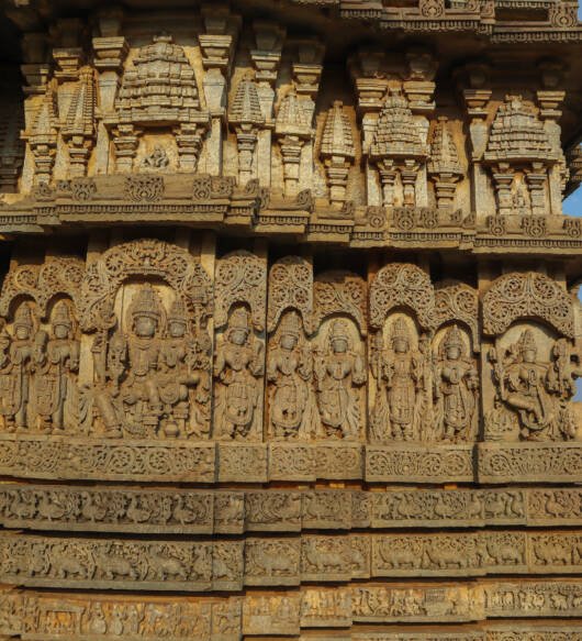 The exterior wall of an old Hoysala Shiva temple with artistic sculptures of mythological deities at Hosaholalu town in India.