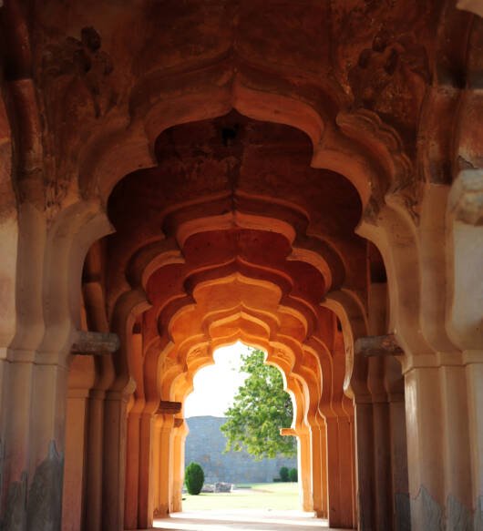 Intricate carvings on the arched hallway Lotus Mahal Temple in Hampi, Karnataka, India. Beautiful carved stone arch. Popular tourist place.