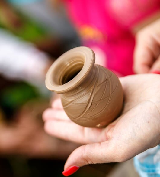Hands working on pottery wheel, making a vase