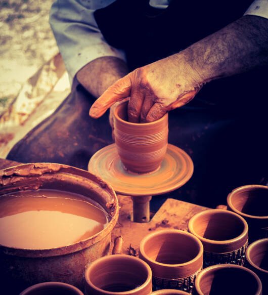 Potter`s hands shaping up the clay of the pot