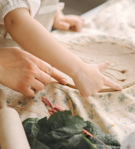 Little girl makes a clay plate and decorates it