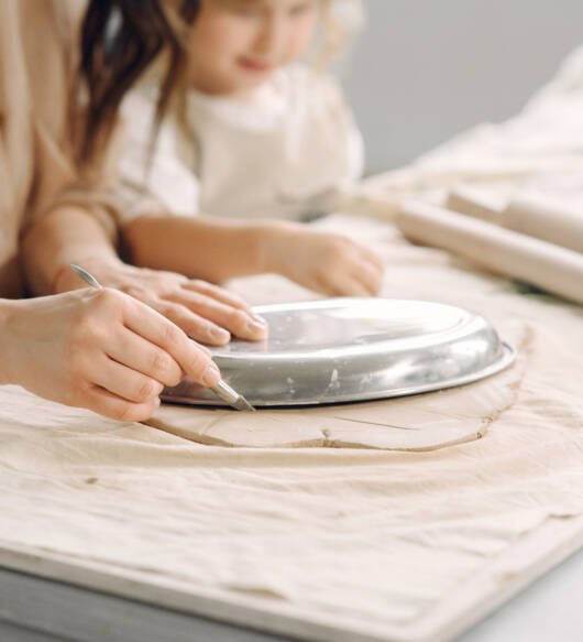 Portrait of mother and little girl shaping clay together